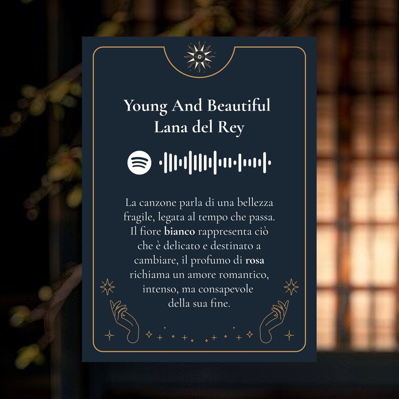 K&ouml;nnte beinhalten: Eine marineblaue Karte mit goldenen Akzenten zeigt den Text "Young And Beautiful" von Lana Del Rey, einen Spotify-Code und italienischen Text. Der italienische Text beschreibt die Themen des Liedes.
