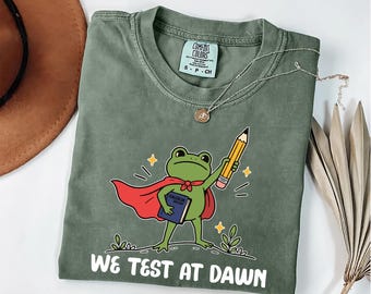 Camiseta Comfort Colors "We Test At Dawn" | Camiseta engraçada de sapo para professor | Camiseta para professor no dia da prova | Presente de agradecimento ao professor | Camiseta com humor para professor