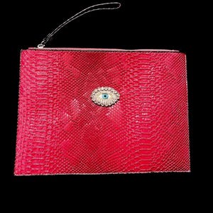 May include: A red clutch with a textured, snake-like pattern. The clutch features a silver zipper and a small silver handle. A decorative eye-shaped embellishment with blue and clear stones is centered on the front.