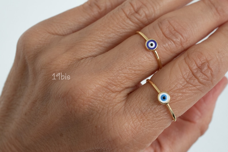 May include: Two gold rings with blue evil eye charms. The rings are thin and delicate.