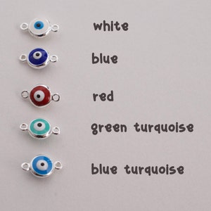 May include: Five silver evil eye charms with different colored enamel inlays. The charms are white, blue, red, green turquoise, and blue turquoise.