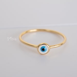 Peut inclure: Une bague en or avec un charme &oelig;il bleu et blanc. La bague est une bande simple avec un charme rond au centre.