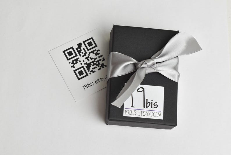 Peut inclure: Une bo&icirc;te cadeau noire avec un ruban argent&eacute; et une &eacute;tiquette blanche avec le texte "19bis.etsy.com" et un code QR. La bo&icirc;te est sur une surface blanche.