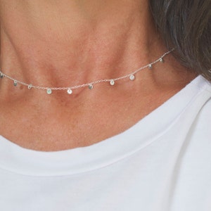 May include: A silver necklace with a delicate chain and small, round pendants.