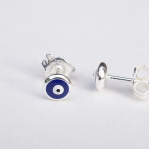 May include: A pair of silver earrings with a blue evil eye design. The earrings are small and delicate, and they would make a great gift for someone special.