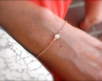 May include: A delicate gold chain bracelet with a single, small, clear gemstone.