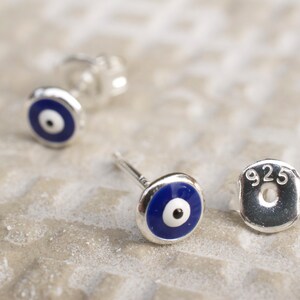 May include: A pair of sterling silver earrings with blue evil eye charms. The earrings are marked with "925" on the back.