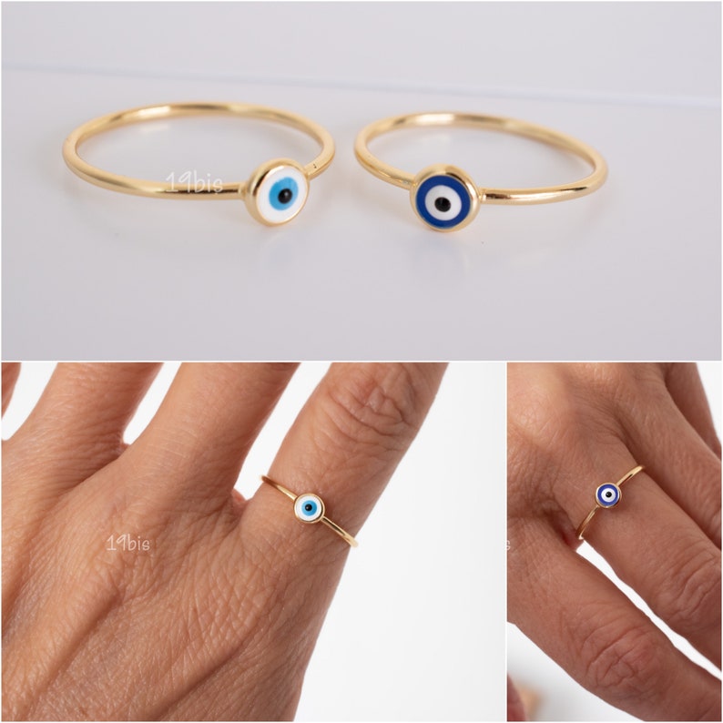 Peut inclure: Deux bagues en or avec un charme &oelig;il bleu et blanc. Les bagues sont pr&eacute;sent&eacute;es sur un fond blanc et sur le doigt d'une personne.