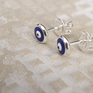 May include: A pair of silver earrings with blue and white evil eye charms. The earrings are a popular symbol of protection and good luck.