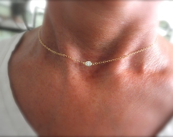 May include: A delicate gold chain necklace with a small, round, clear gemstone pendant.