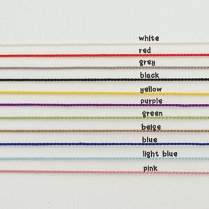 May include: A collection of 12 spools of embroidery floss in various colors, including white, red, grey, black, yellow, purple, green, beige, blue, light blue, and pink.