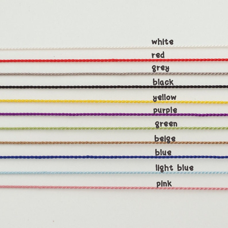 May include: A collection of 12 spools of embroidery floss in various colors, including white, red, grey, black, yellow, purple, green, beige, blue, light blue, and pink.