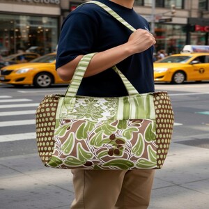 Puede incluir: Un bolso tote rectangular con un dise&ntilde;o de patchwork que combina varios patrones en tonos verdes y marrones. El bolso incluye paneles laterales con lunares marrones y verdes, una secci&oacute;n central con hojas y asas a rayas.