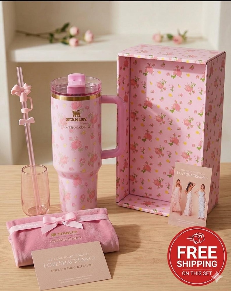 K&ouml;nnte beinhalten: Ein rosa Stanley-Becher mit Blumenmuster, Griff, passendem Strohhalm und kleinem Glas. Das Set enth&auml;lt eine rosa Schachtel mit Blumenmustern, einen Samtbeutel und eine Karte mit "LOVESHACKFANCY". Der Becher hat die Logos Stanley und LOVESHACKFANCY.