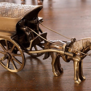 Può includere: Miniatura in ottone di una carrozza trainata da cavalli. La carrozza ha un tetto dettagliato e ruote a raggi. Il cavallo è attaccato alla carrozza con le redini. Il design è ornato e vintage.