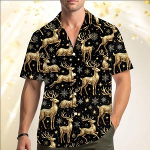 May include: A short-sleeved button-down shirt in black featuring a repeating pattern of gold-colored reindeer in various poses, interspersed with gold-colored snowflakes and small star shapes across the entire fabric of the garment.
