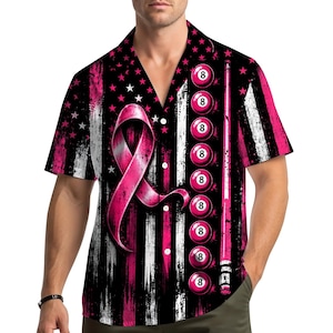 May include: A short-sleeved button-down shirt featuring a black and pink distressed American flag pattern. The design includes a large pink awareness ribbon on the left side, a vertical row of eight pink billiard balls, and a pink pool cue stick.