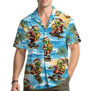 May include: A short-sleeve button-down shirt featuring a repeating pattern of green aliens wearing red and white Santa hats and suits, each holding an orange cat while riding a skateboard, set against a tropical beach background with blue ocean waves.