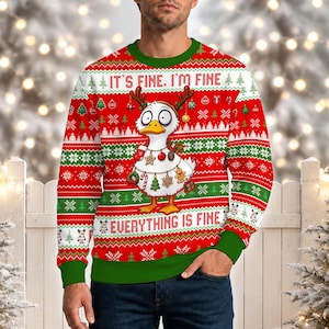 May include: A red, green, and white long-sleeve crewneck jumper featuring a cartoon duck with wide eyes and reindeer antlers. The text IT'S FINE. I'M FINE and EVERYTHING IS FINE is printed on the front, surrounded by festive holiday patterns.