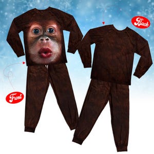 Puede incluir: Un conjunto de pijama de dos piezas con camisa de manga larga y pantalón con estampado de pelaje marrón oscuro. La parte delantera de la camisa muestra un rostro realista de orangután con ojos grandes y labios rojos fruncidos.