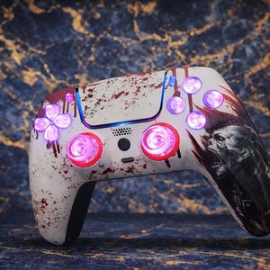 Könnte beinhalten: Benutzerdefinierter weißer Gaming-Controller mit Zombie-Design. Der Controller verfügt über rot und violett beleuchtete Tasten und einen Spritzeffekt. Die rechte Seite hat eine detaillierte Zombie-Grafik.