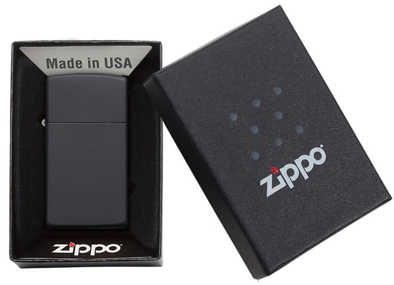 以下が含まれることがあります： 黒色のマットなZippoライターが黒い箱に入っています。箱は開いており、ライターと「Made in USA」の文字が見えます。Zippoのロゴが箱とライターに表示されています。