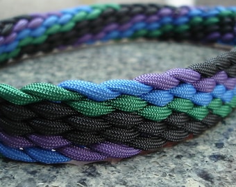 Könnte beinhalten: Ein geflochtenes Paracord-Armband mit schwarzen, grünen, blauen und violetten Strängen.
