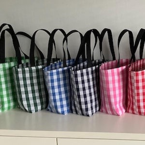 May include: A collection of tote bags in various colors, each featuring a classic gingham pattern. The bags have black handles and are arranged in a row. Colors include green, blue, pink, red, and purple.