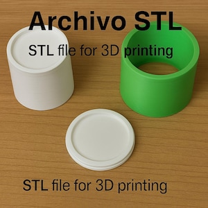Puede incluir: Tres objetos impresos en 3D: un recipiente cilíndrico blanco con tapa, un anillo cilíndrico verde y una tapa blanca. El texto "Archivo STL" y "STL file for 3D printing" son visibles.