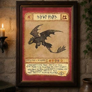 Op de afbeelding: Een ingelijste illustratie van een zwarte draak met gele ogen op een achtergrond in perkamentstijl. Het kunstwerk heeft een donkerbruine houten lijst en bevat gestileerde tekst. Het thema is fantasy-kunst.