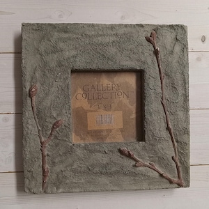 May include: A square gray picture frame with a rough, textured surface featuring raised brown twig and bud details on the left and right sides. The center insert displays the text GALLERY COLLECTION 3 x 3 with a barcode and product information.