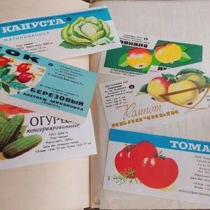 May include: A collection of vintage food labels featuring illustrations of cabbage, rose hips, apples, cucumbers, and tomatoes. The labels are in Russian and have a retro aesthetic, with vibrant colors and detailed drawings of the produce.