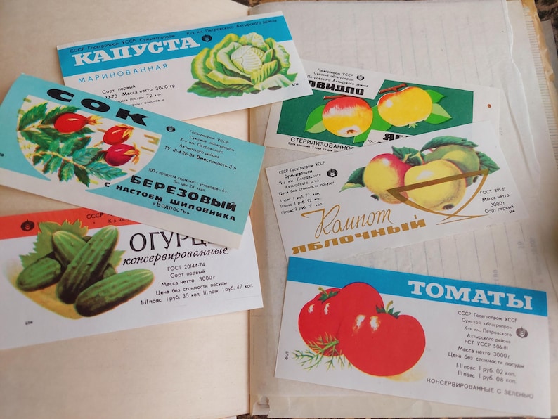 May include: A collection of vintage food labels featuring illustrations of cabbage, rose hips, apples, cucumbers, and tomatoes. The labels are in Russian and have a retro aesthetic, with vibrant colors and detailed drawings of the produce.