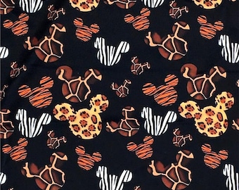 May include: Black fabric featuring a repeating pattern of Mickey Mouse heads in animal print designs. The prints include zebra stripes, giraffe spots, and leopard spots. White zebra stripes and small Mickey Mouse heads are also scattered across the fabric.