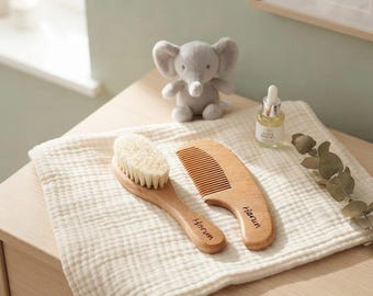 May include: A wooden hairbrush and a wooden comb, both engraved with the name Harun, resting on a cream-colored muslin cloth. The set is accompanied by a small gray plush elephant toy and a clear glass dropper bottle with a white cap.