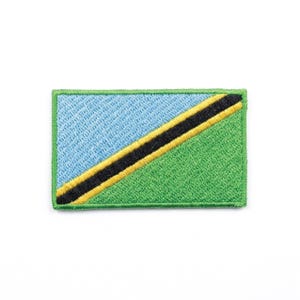 May include: Embroidered patch depicting the Tanzanian flag. The rectangular patch features a light blue section in the upper left and a green section in the lower right, separated by a black diagonal stripe with yellow borders. The patch is edged in green.
