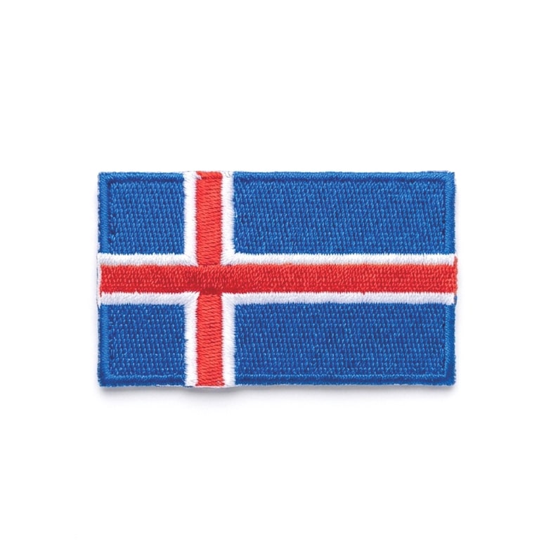 May include: A rectangular patch featuring the flag of Iceland. The flag has a blue background with a red cross outlined in white. The cross extends to the edges of the patch. The patch is made of fabric.