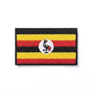 Könnte beinhalten: Gestickter Aufnäher mit der Flagge von Uganda. Der rechteckige Aufnäher hat horizontale Streifen in Schwarz, Gelb und Rot. Ein weißer Kreis in der Mitte zeigt einen grauen Kranich mit roten Akzenten. Der Aufnäher hat einen schwarzen Rand.