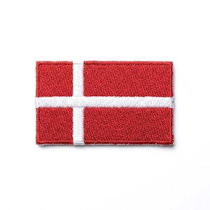 May include: Embroidered patch featuring the flag of Denmark. The rectangular patch has a red background with a white Scandinavian cross design. The patch is likely for clothing or accessories.