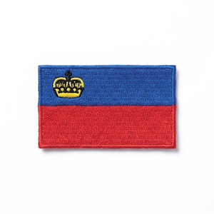 Puede incluir: Parche bordado rectangular con la bandera de Liechtenstein. El diseño incluye una sección superior azul, una sección inferior roja y un emblema de corona dorada en la esquina superior izquierda. El parche tiene un borde cosido.