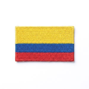 May include: Embroidered patch depicting the flag of Colombia. The rectangular patch shows the flag's horizontal stripes in yellow, blue, and red. The patch has a yellow border and is designed to be sewn or ironed onto fabric.
