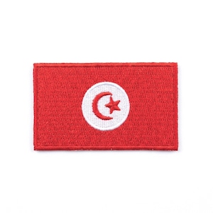 Peut inclure: Un écusson rectangulaire rouge représentant le drapeau tunisien. Le drapeau présente un cercle blanc au centre, contenant un croissant rouge et une étoile rouge.