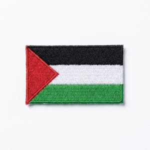 Può includere: Toppa ricamata con la bandiera palestinese. Il design della bandiera presenta strisce orizzontali nere, bianche e verdi, con un triangolo rosso sul lato sinistro. La toppa è di forma rettangolare.