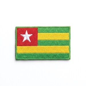 Peut inclure: Écusson brodé représentant le drapeau du Togo. Le drapeau comprend un carré rouge avec une étoile blanche, et des rayures horizontales jaunes et vertes alternées. L'écusson a une bordure verte.