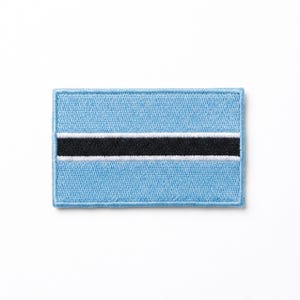 May include: A rectangular patch featuring the flag of Botswana. The flag has a light blue background with a horizontal black stripe in the center, edged with white. The patch is embroidered with a textured appearance.