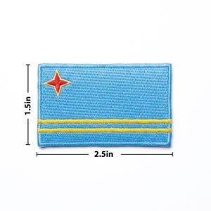 May include: Embroidered patch featuring the flag of Aruba. The rectangular patch is light blue with a red four-pointed star in the upper left corner and two yellow horizontal stripes. The patch measures 2.5 inches wide and 1.5 inches high.