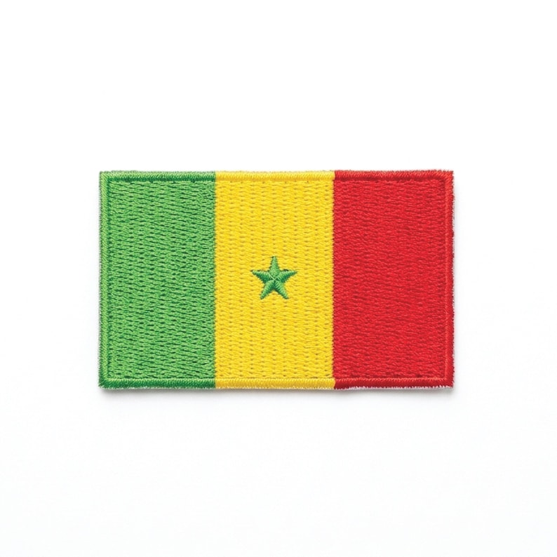 May include: Embroidered patch featuring the flag of Senegal. The rectangular patch displays vertical stripes of green, yellow, and red. A green star is centered on the yellow stripe. The patch has a stitched border.