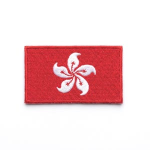 May include: A rectangular red patch featuring the Hong Kong flag. The flag design includes a white, five-petal Bauhinia flower with red stamens. The patch is likely an embroidered emblem.