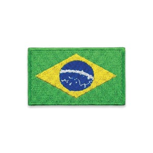 Peut inclure: Un écusson brodé rectangulaire représentant le drapeau national du Brésil. Le motif se compose d'un fond vert avec un losange jaune central contenant un cercle bleu. Une bande blanche incurvée avec des points blancs traverse le cercle.