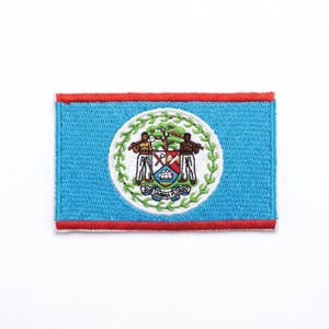 Può includere: Toppa ricamata raffigurante la bandiera del Belize. La toppa ha uno sfondo azzurro con un bordo rosso. Il centro presenta un cerchio bianco con lo stemma del Belize, che include due figure, un albero e la scritta "SUB UMBRA FLOREO".